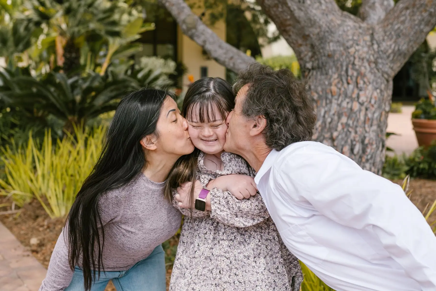 Una mamá y un papá abrazan a su hija con síndrome de Down